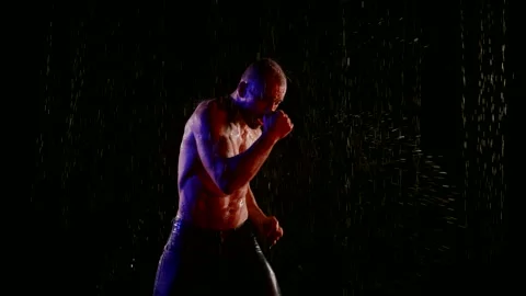 Boxer is training alone in rain in night, punching by hands to air Vídeo Stock 165934178