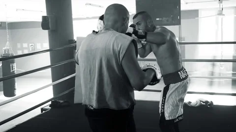 Boxer training with coach on ring with gloves black and white Stock Footage 82273735