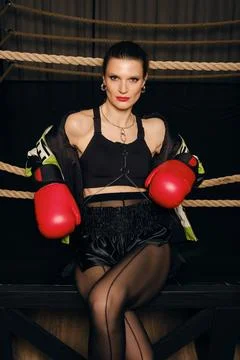 Boxer training in a gym setting wearing red gloves and focused on her worko.. Stock Photos