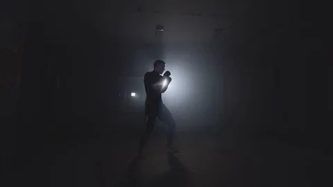 Boxer training in low light gym in slow motion. Sportsman boxing in smoky studio Stock Footage 96082497