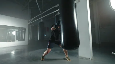 Boxer training with punching bag in spacious gym Stock Footage 309962133