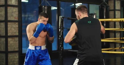 Boxer training uppercut punches in boxing club 4k video. Fighter with trainer Stock Footage 70394339