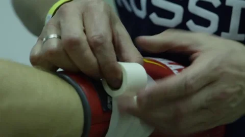 Boxer wearing boxing gloves against black background. Man helps to wear a Boxing Stock Footage