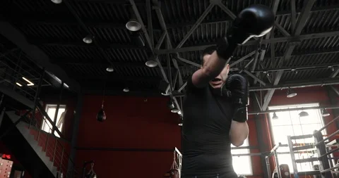 Boxer young man in gloves boxing and looking at camera in gym, bottom view. Stock Footage 127101805