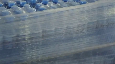 Boxes with bottles of water are packed in polyethylene tape. Stock Footage 81124395