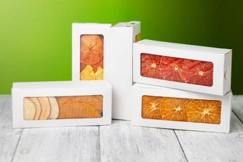 Boxes of fruit chips lie on a white wooden background, back light green Stock Photos