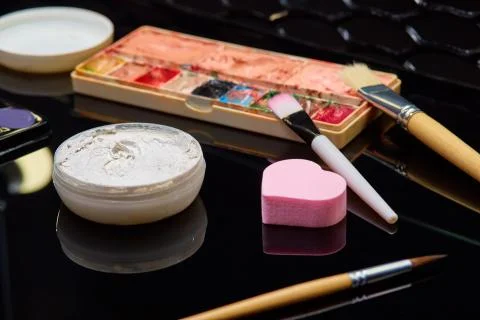 Boxes of makeup, brushes, sponge are on the black table Stock Photos