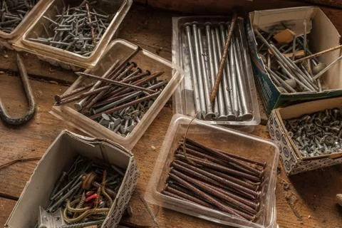 Boxes of screws and nails, some rusting, some brand new on a wooden work top Stock Photos