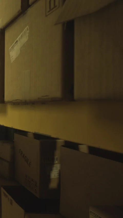 Boxes stacked high in a dimly lit storage area during evening hours Stock Footage 334243633