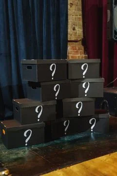 Boxes stacked on a stage with question marks, indicating a mystery Stock Photos