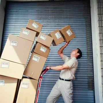 Boxes tipping on delivery man 写真素材