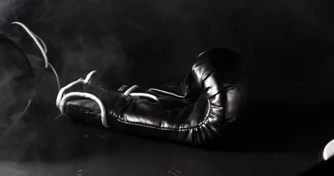 Boxing gloves falling through smoke close up isolated on black Stock Footage 205043082