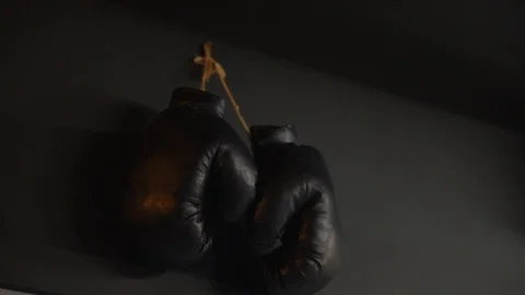 Boxing gloves hang on the background of a dark wall Stock Footage 122212664