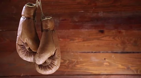 Boxing gloves hanging and rotating on wooden background. Vídeo Stock 50217652