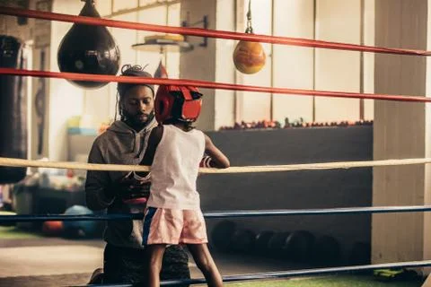 Boxing kid standing inside the ring talking to his trainer. 스톡 사진