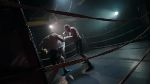 Boxing match with the referee in a dimly lit boxing ring. Stock Footage 302730917