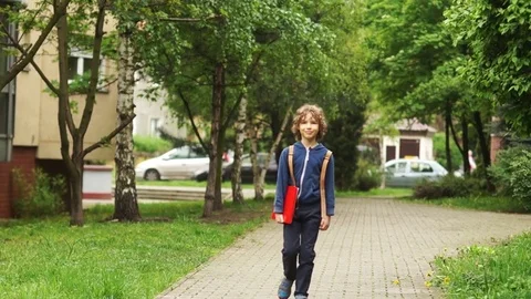 A boy of 10-11 years old goes home from school. Behind him, he carries a Video stock 77830586