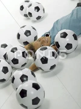 Boy (10-13) lying between football Stock Photos