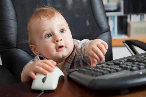 Boy, 10 months, using a computer mouse and keyboard Foto stock