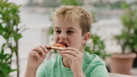 A boy of 10 years eats pizza with pleasure Stock Footage 131876496