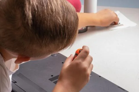 A boy of 10 years old is sorting a laptop for cleaning and maintenance. Selec Stock Photos