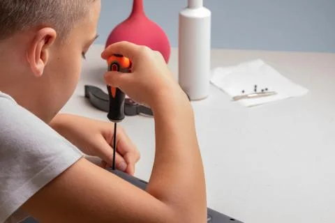A boy of 10 years old is sorting a laptop for cleaning and maintenance. Selec Stock Photos