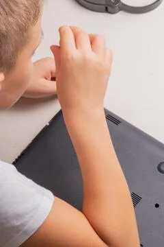 A boy of 10 years old is sorting a laptop for cleaning and maintenance. Selec Stock Photos