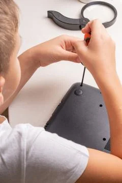A boy of 10 years old is sorting a laptop for cleaning and maintenance. Selec Stock Photos