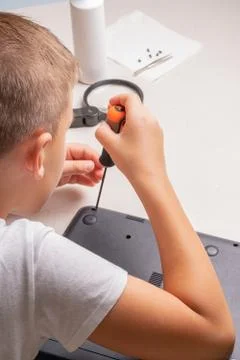 A boy of 10 years old is sorting a laptop for cleaning and maintenance. Selec Stock Photos