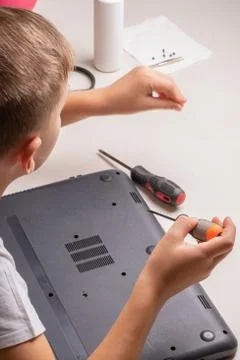 A boy of 10 years old is sorting a laptop for cleaning and maintenance. Selec Stock Photos