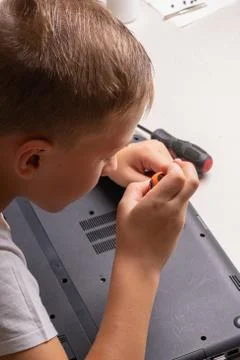 A boy of 10 years old is sorting a laptop for cleaning and maintenance. Selec Stock Photos