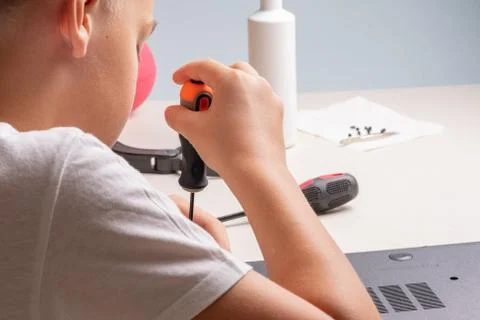 A boy of 10 years old is sorting a laptop for cleaning and maintenance. Selec Stock Photos