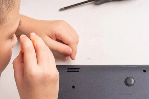 A boy of 10 years old is sorting a laptop for cleaning and maintenance. Selec Stock Photos