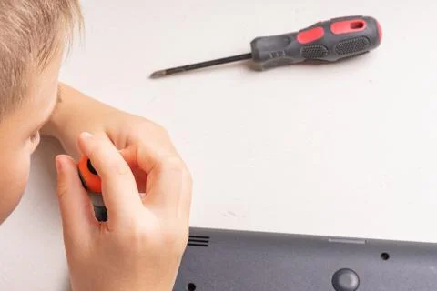 A boy of 10 years old is sorting a laptop for cleaning and maintenance. Selec Stock Photos
