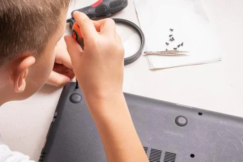 A boy of 10 years old is sorting a laptop for cleaning and maintenance. Selec Stock Photos
