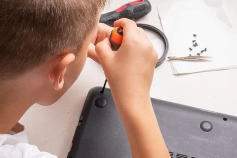 A boy of 10 years old is sorting a laptop for cleaning and maintenance. Selec Stock-Fotos