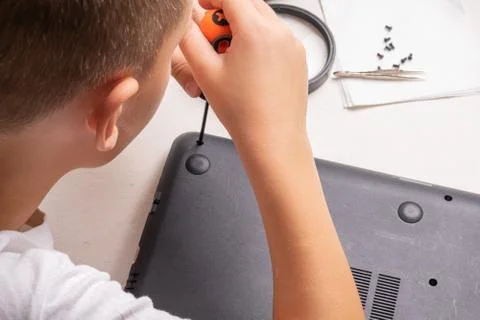 A boy of 10 years old is sorting a laptop for cleaning and maintenance. Selec Stock Photos