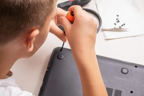 A boy of 10 years old is sorting a laptop for cleaning and maintenance. Selec Stock Photos