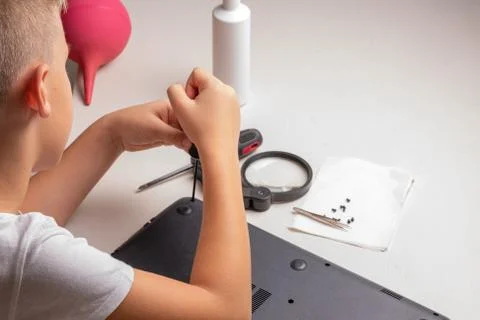 A boy of 10 years old is sorting a laptop for cleaning and maintenance. Selec Stock Photos