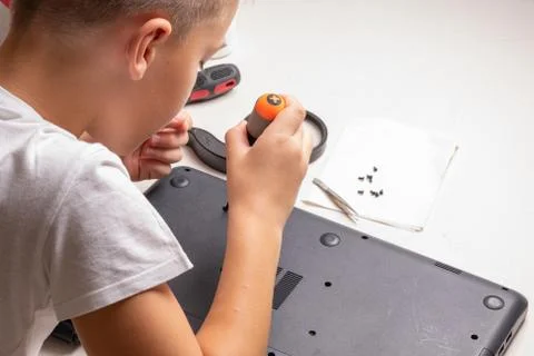 A boy of 10 years old is sorting a laptop for cleaning and maintenance. Selec Stock Photos