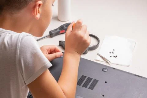 A boy of 10 years old is sorting a laptop for cleaning and maintenance. Selec Stock Photos