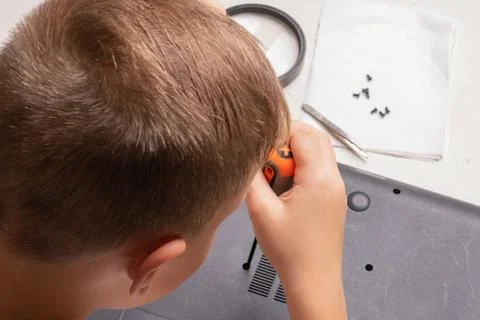 A boy of 10 years old is sorting a laptop for cleaning and maintenance. Selec Stock Photos