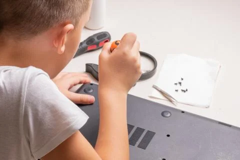A boy of 10 years old is sorting a laptop for cleaning and maintenance. Selec Stock Photos
