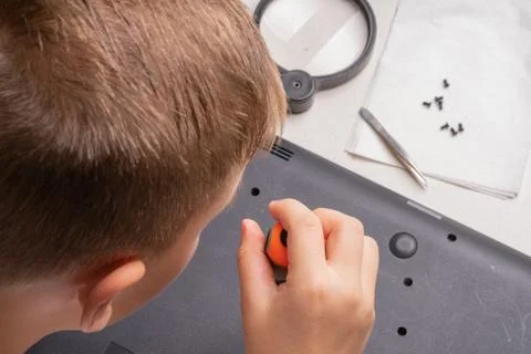 A boy of 10 years old is sorting a laptop for cleaning and maintenance. Selec Stock Photos