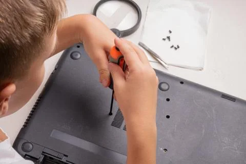 A boy of 10 years old is sorting a laptop for cleaning and maintenance. Selec Stock Photos