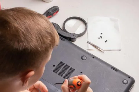 A boy of 10 years old is sorting a laptop for cleaning and maintenance. Selec Stock Photos