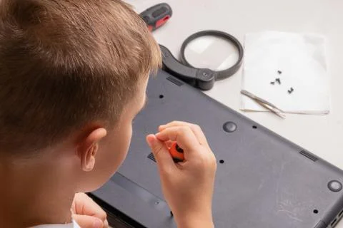 A boy of 10 years old is sorting a laptop for cleaning and maintenance. Selec Stock Photos