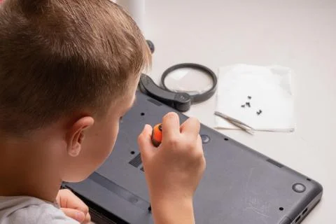 A boy of 10 years old is sorting a laptop for cleaning and maintenance. Selec Stock Photos
