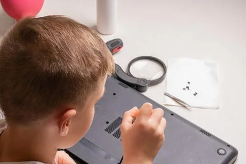 A boy of 10 years old is sorting a laptop for cleaning and maintenance. Selec Stock Photos