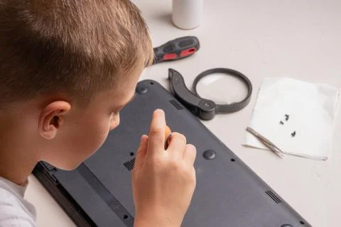 A boy of 10 years old is sorting a laptop for cleaning and maintenance. Selec Stock Photos